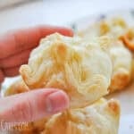 a hand holding golden brown baked brie bites