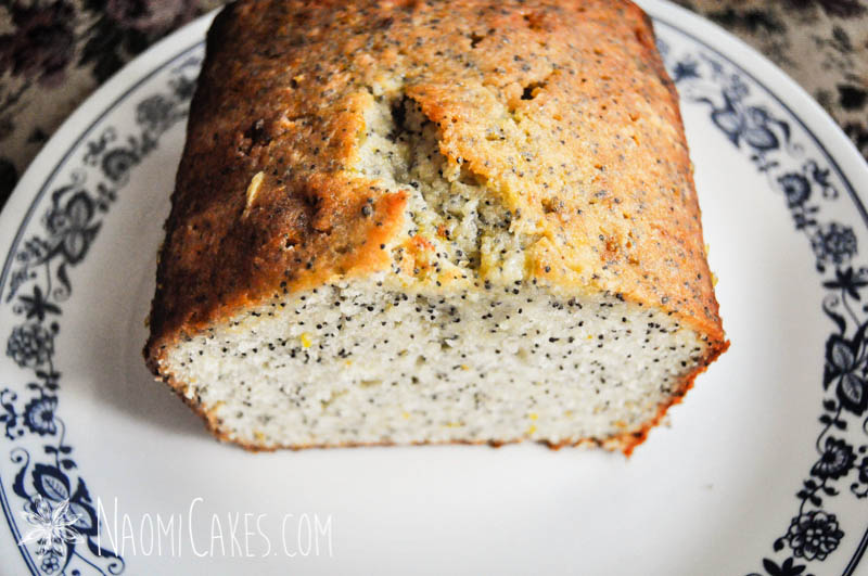 a sliced open loaf of orange poppyseed pound cake on a plate