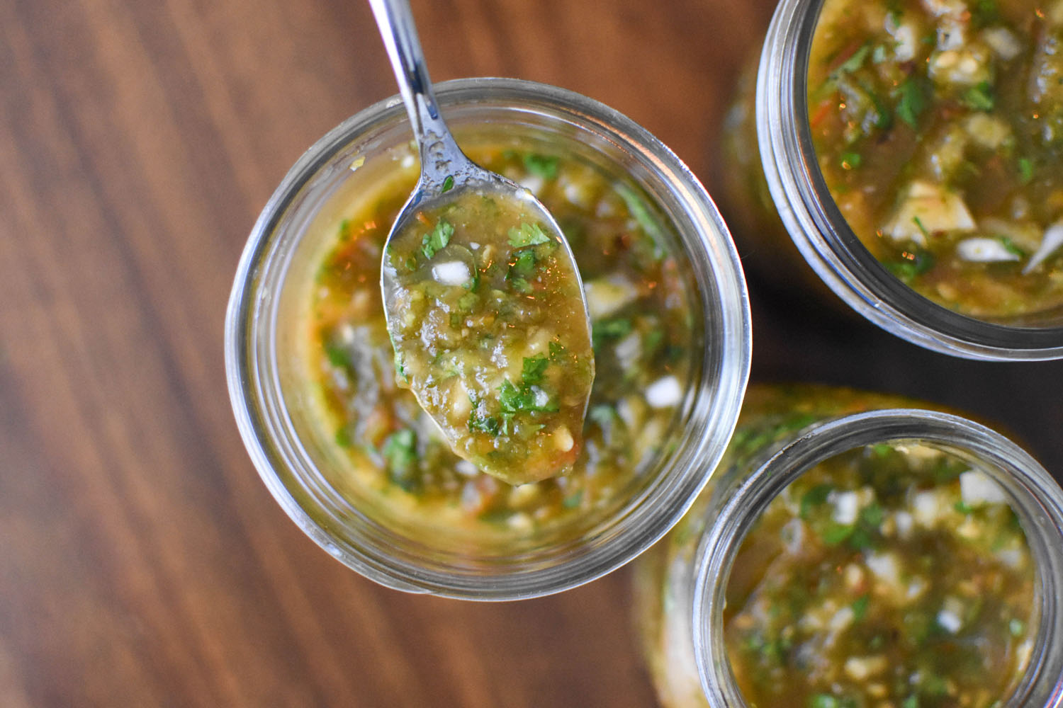 3 jars of fresh green chile with a spoon showing what it looks like