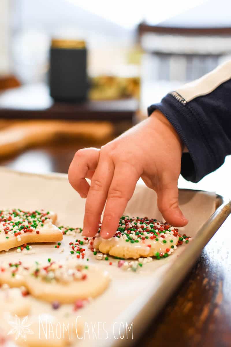 toddler hand picking up a Christmas sugar cookie