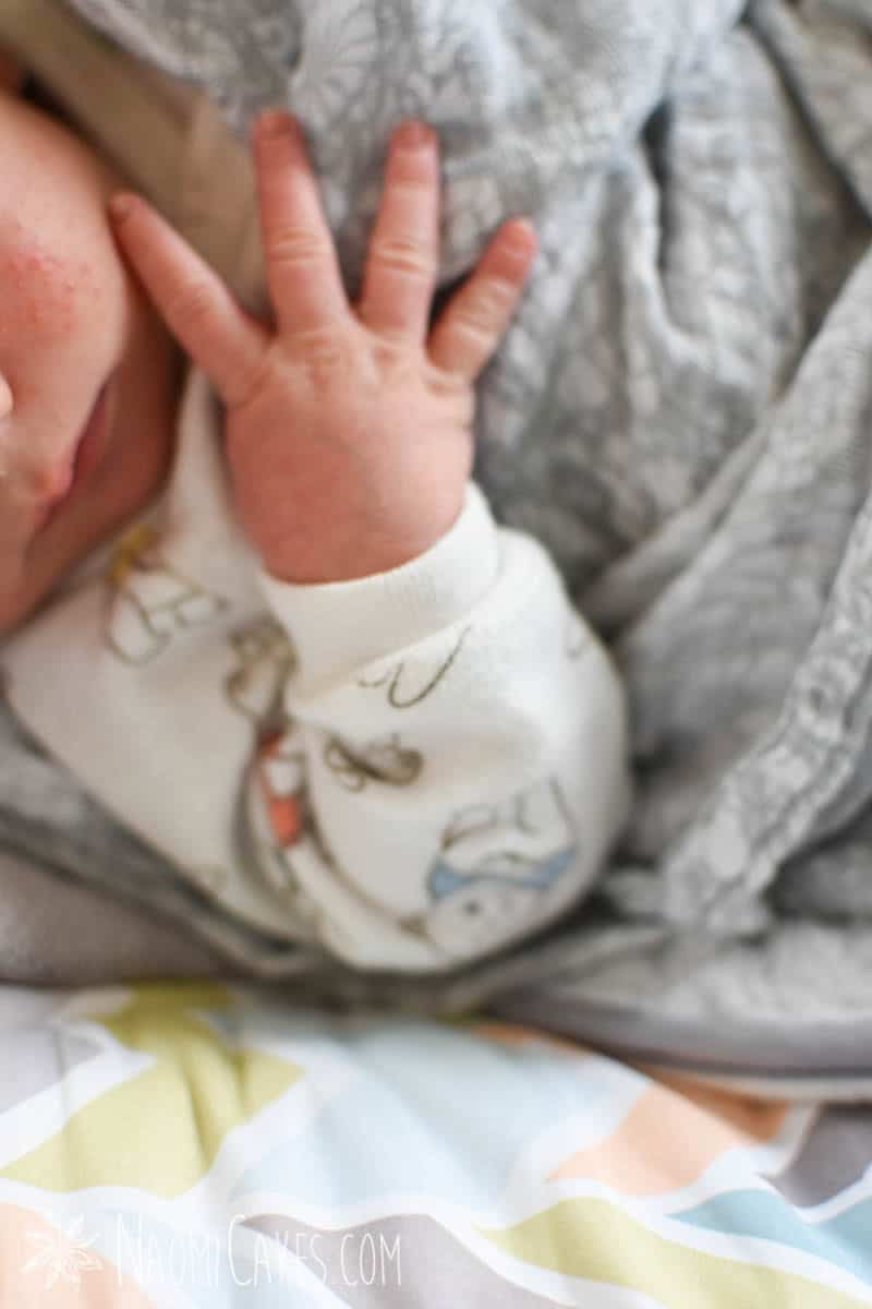 baby hand on a grey blanket as a featured image in an unmedicated VBAC birth story