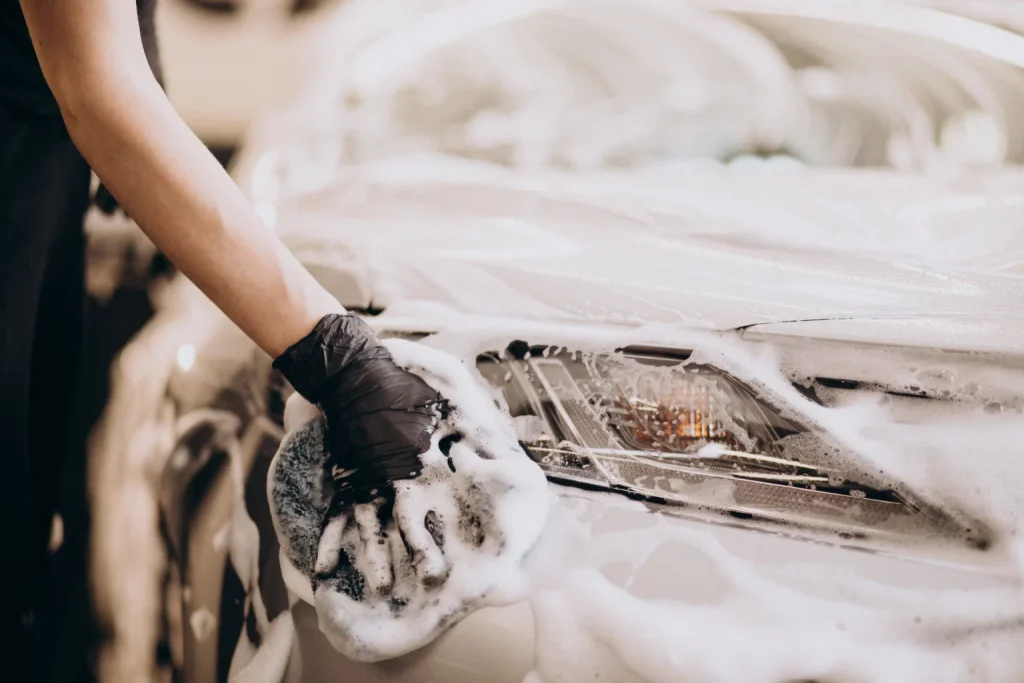 A person washing a car with a sponge.