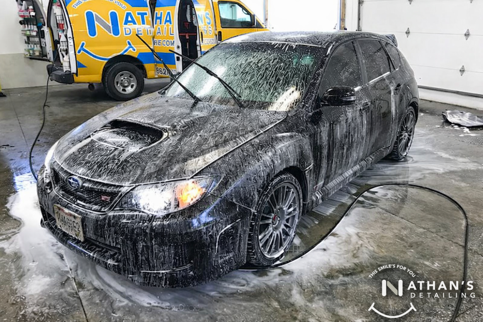 Foam wash on black car in garage during mobile detailing
