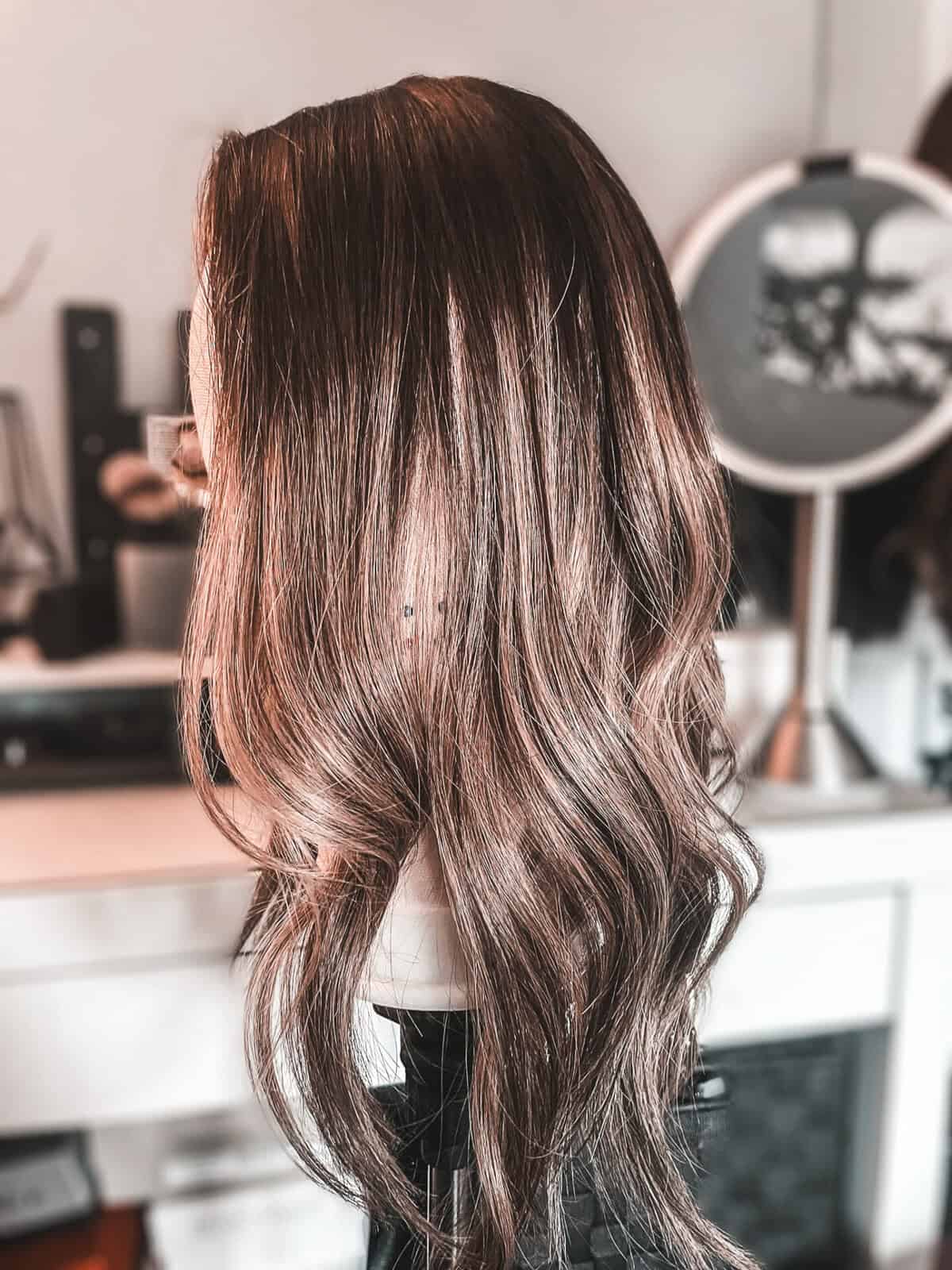 Woman adjusting a clip-in hair topper to stop it sliding on fine thinning hair
