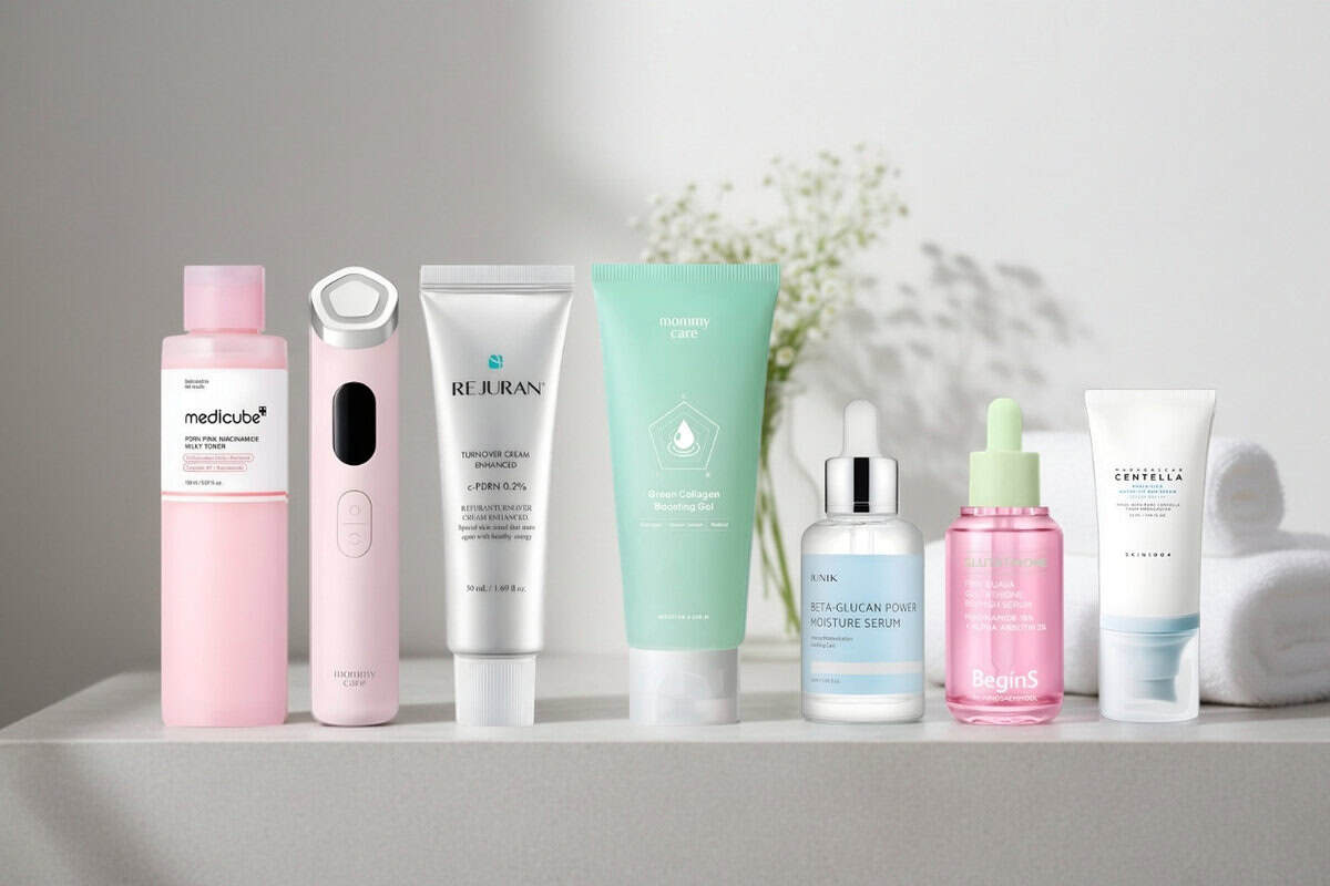 Seven K-beauty products from my STYLEVANA box lined up on a light grey shelf: Medicube PDRN toner, mommy care Penta Prime, Rejuran Turnover Cream, mommy care Green Collagen Gel, iUNIK Beta Glucan serum, BeginS Pink Guava serum and SKIN1004 sun serum