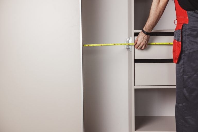 A carpenter measures the interior of a cabinet, ensuring precise dimensions for a perfect fit.