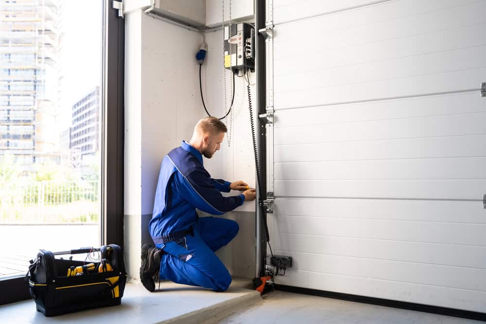 A technician meticulously works on an industrial garage door, ensuring everything is in perfect order.