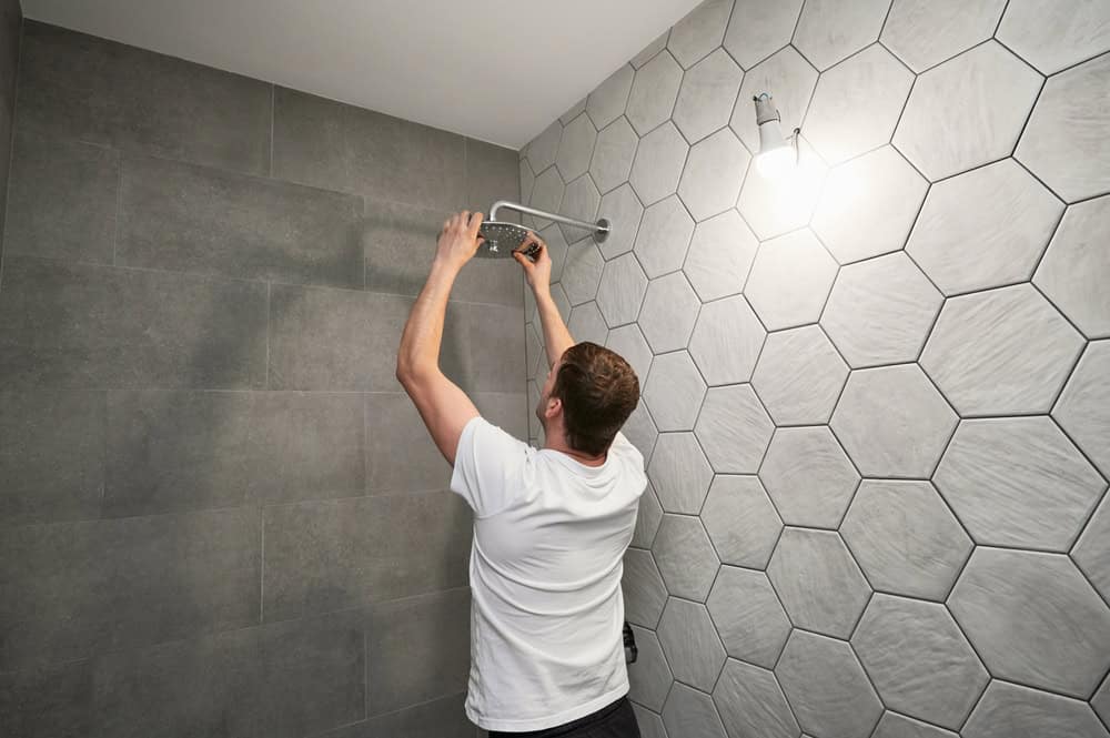 Installing a new showerhead in a modern, tiled bathroom.
