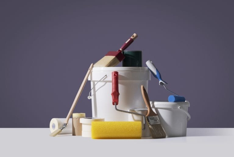 A painter's toolkit: buckets, brushes, rollers, and tape, ready for a creative transformation.