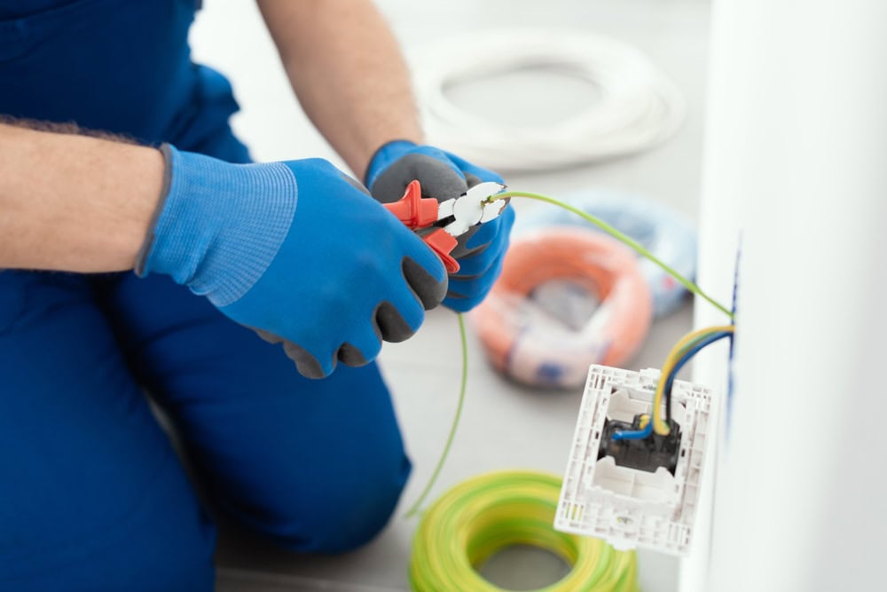 An electrician carefully wires an electrical outlet, ensuring safety and precision.
