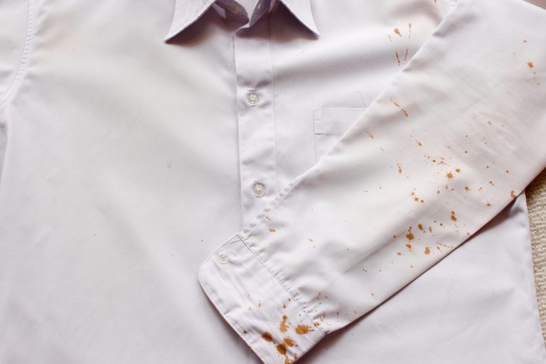 A crisp white dress shirt marred by scattered rust-colored stains, suggesting an unfortunate encounter with coffee or food spills.