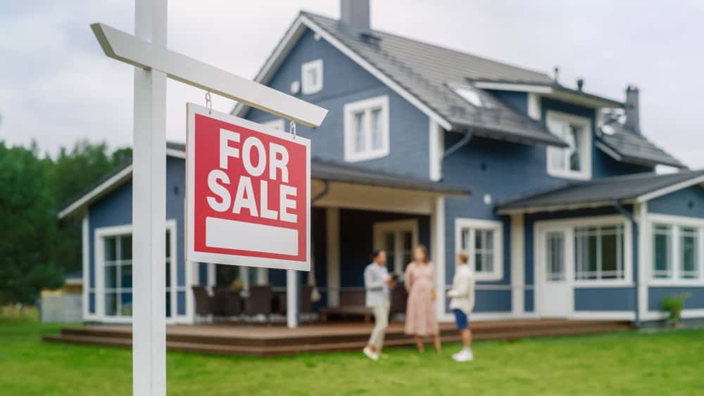 Dream home alert! "For Sale" sign on this stunning blue house.
