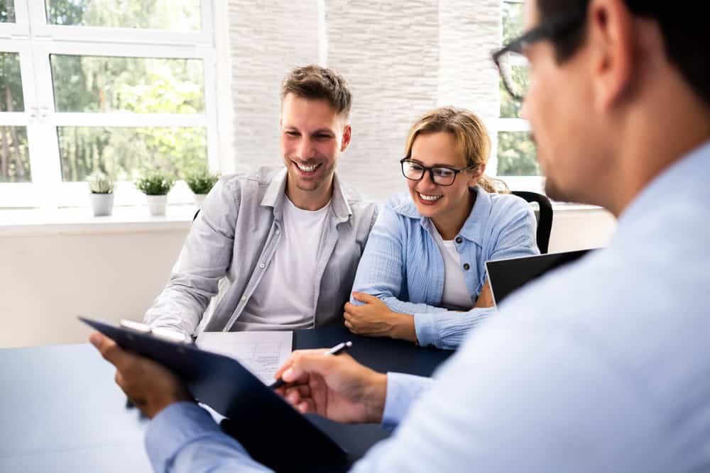 Couple smiles as they review financial documents with their advisor.