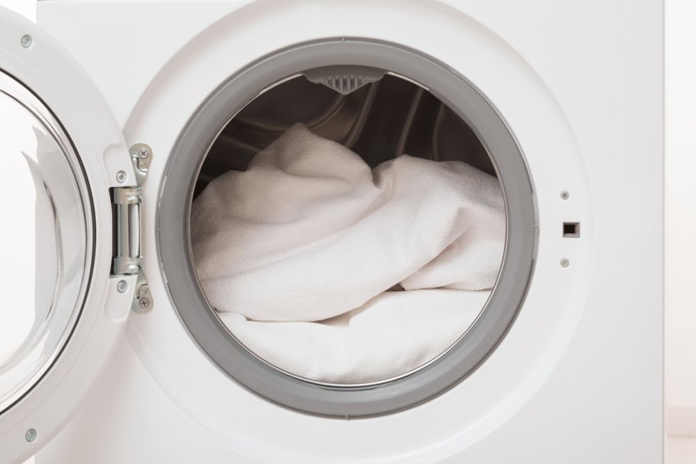 Freshly laundered towels tumble in a modern front-loading washing machine.