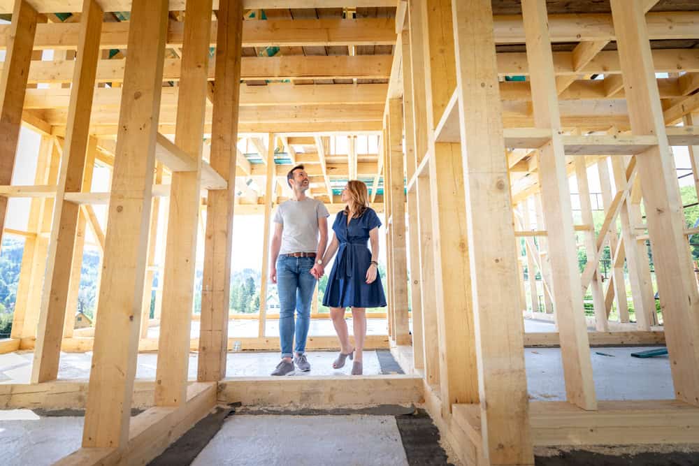 A couple walks hand in hand through the wooden frame.