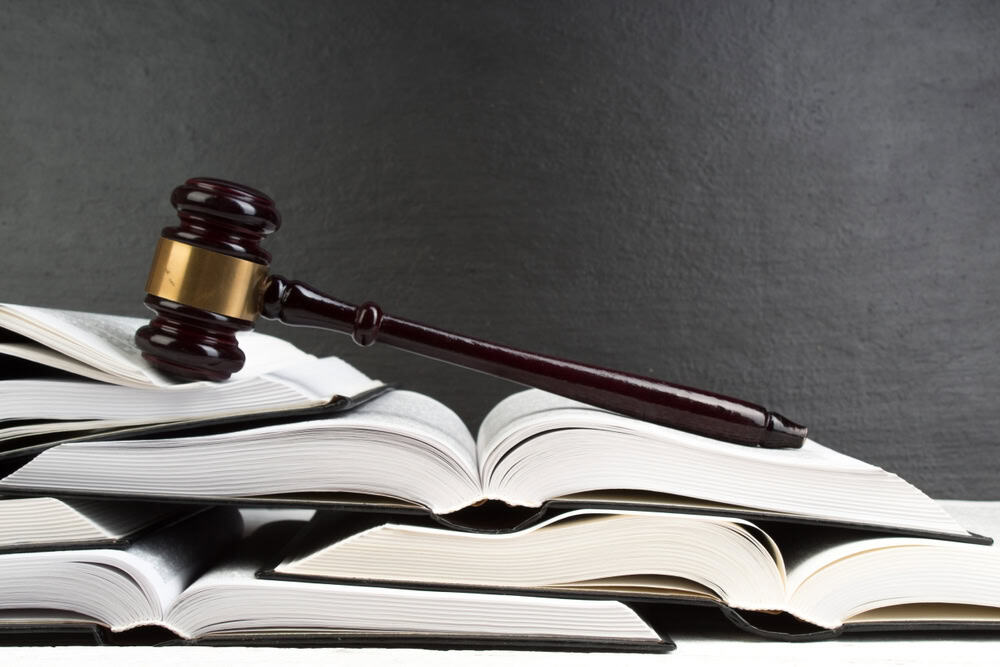 A judge's gavel rests atop a stack of open law books.
