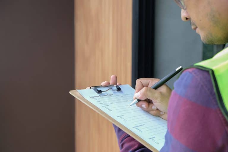 A home inspector working through a checklist on a clipboard