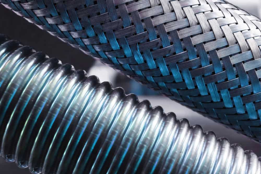 "Industrial elegance: a close-up of braided and coiled metal hoses in perfect harmony.