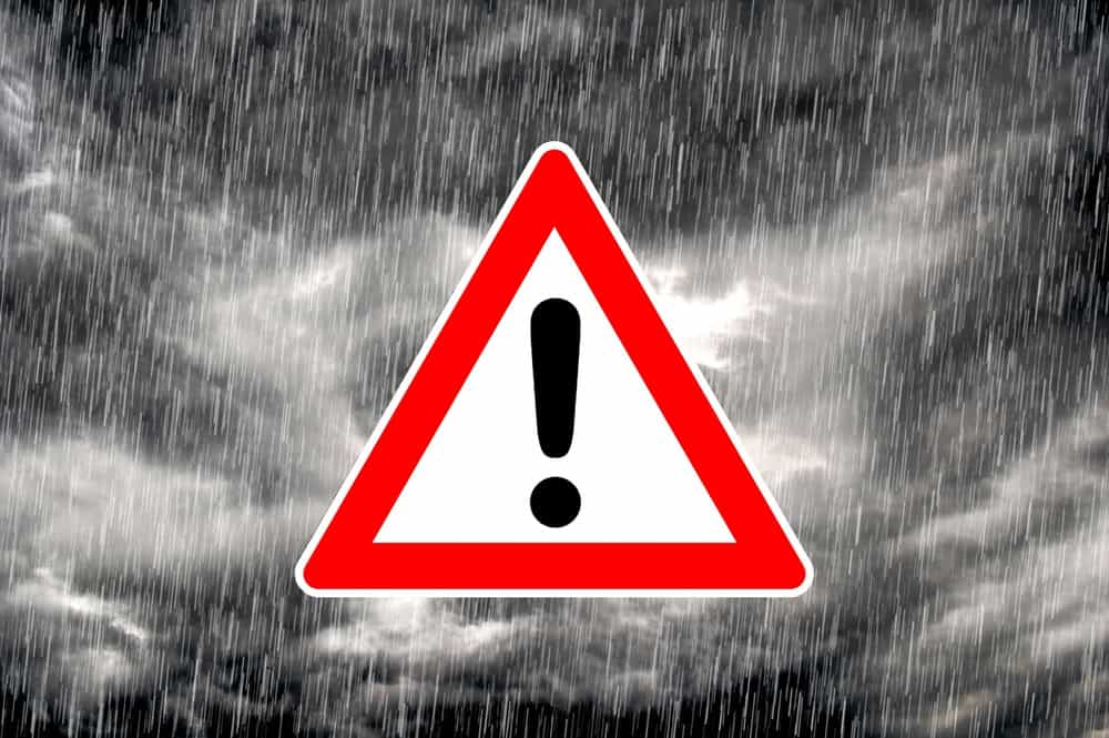 Warning sign amidst a stormy, rainy sky.