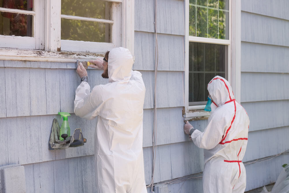 Safely restoring a home—workers in protective suits remove old paint with precision.