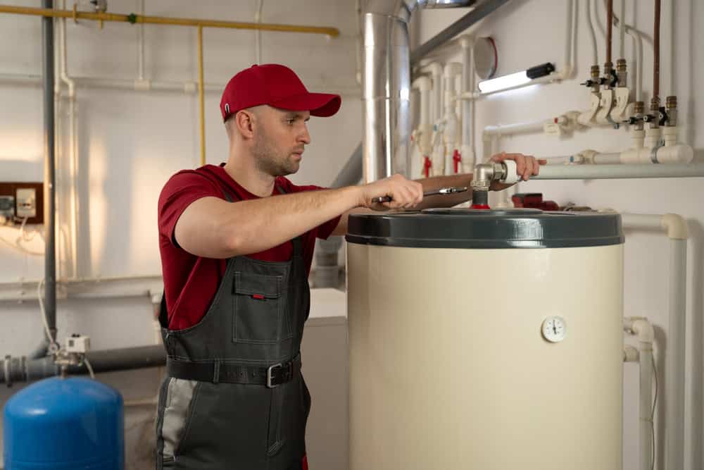 A technician diligently works on a water heater in a well-equipped utility room.