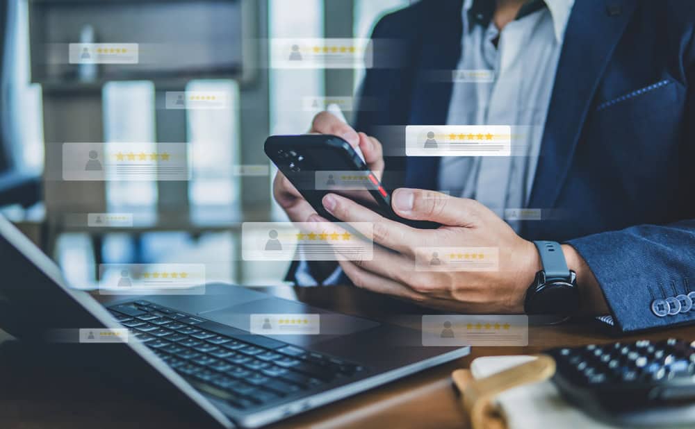 Managing customer reviews on the go with a smartphone while working at the desk.
