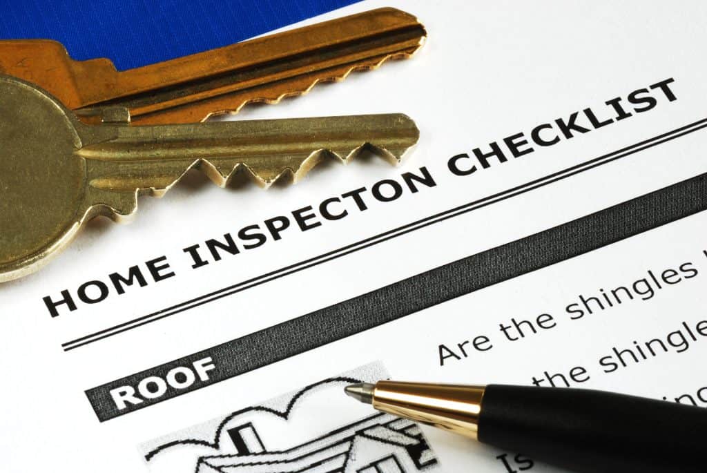A home inspection checklist lays flat with a pen pointing towards the first item.
