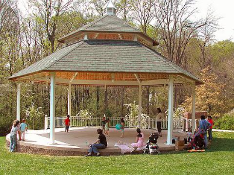 A covered wooden gazebo with families gathered underneath, at McLean Central Park in McLean, Virginia.