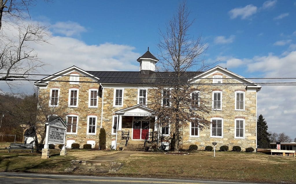 A bare tree stands before the stone Old Stone School building in Hillsboro, Virginia