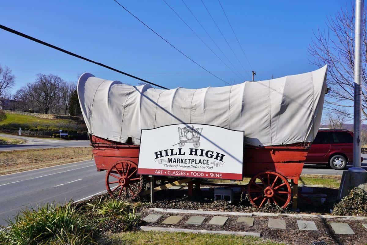 A covered wagon marks the sign for Hill High Marketplace along a road in Round Hill, Virginia