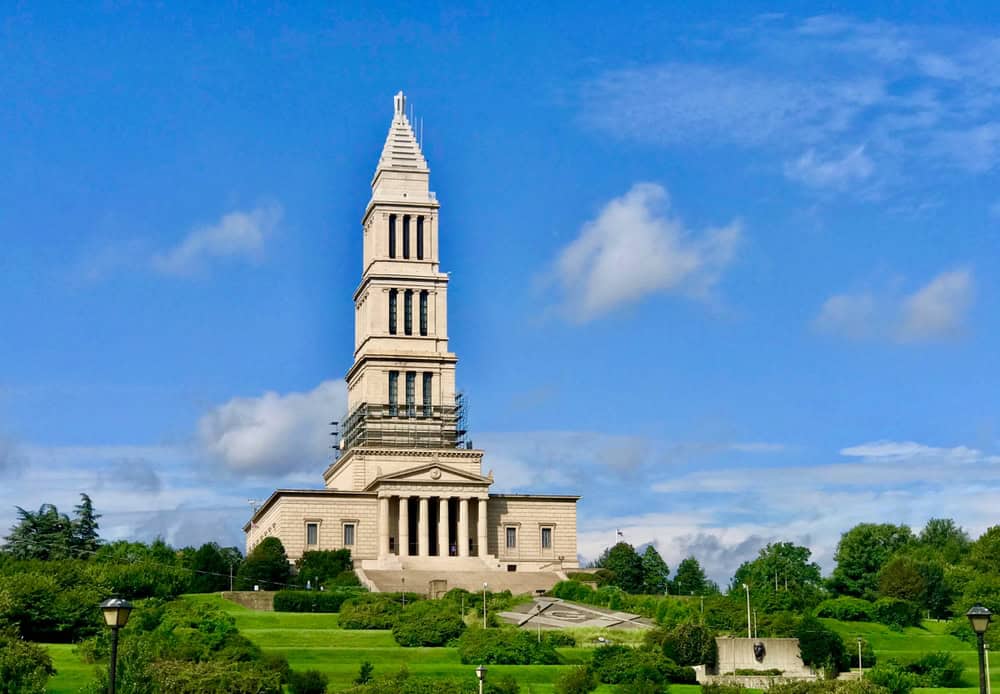 The George Washington Masonic Memorial tower rising above trees under a blue sky in Alexandria, Virginia.