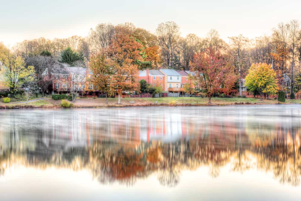 Townhouses and homes with autumn foliage reflected in the still water of Burke Lake in Burke, Virginia.