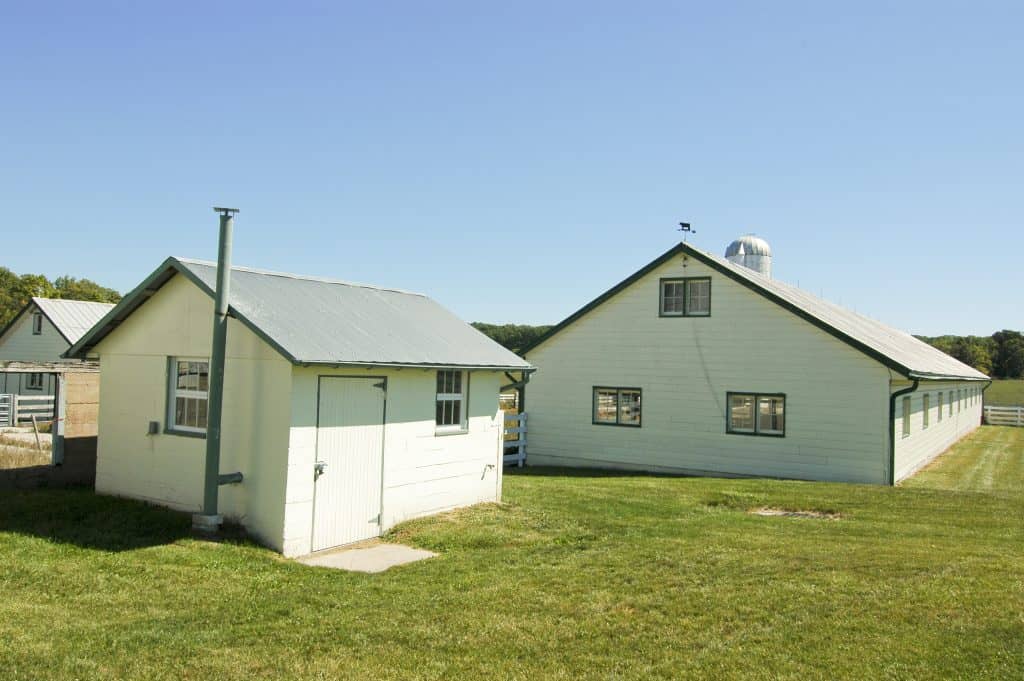 White farm outbuildings with green trim and a silo on a grassy lot in Adams County, Pennsylvania.