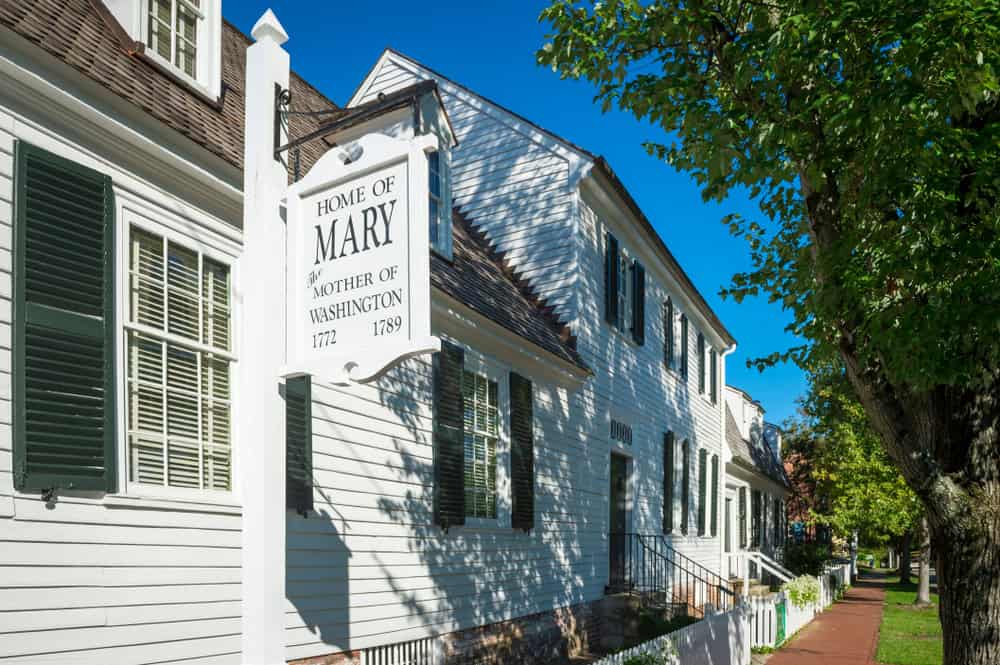 A sign marking the historic home of Mary Washington on a tree lined street in Fredericksburg, Virginia