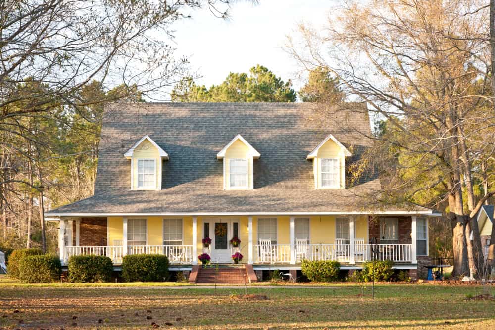 A yellow farmhouse with a wraparound porch and three dormer windows in New Oxford, Pennsylvania.
