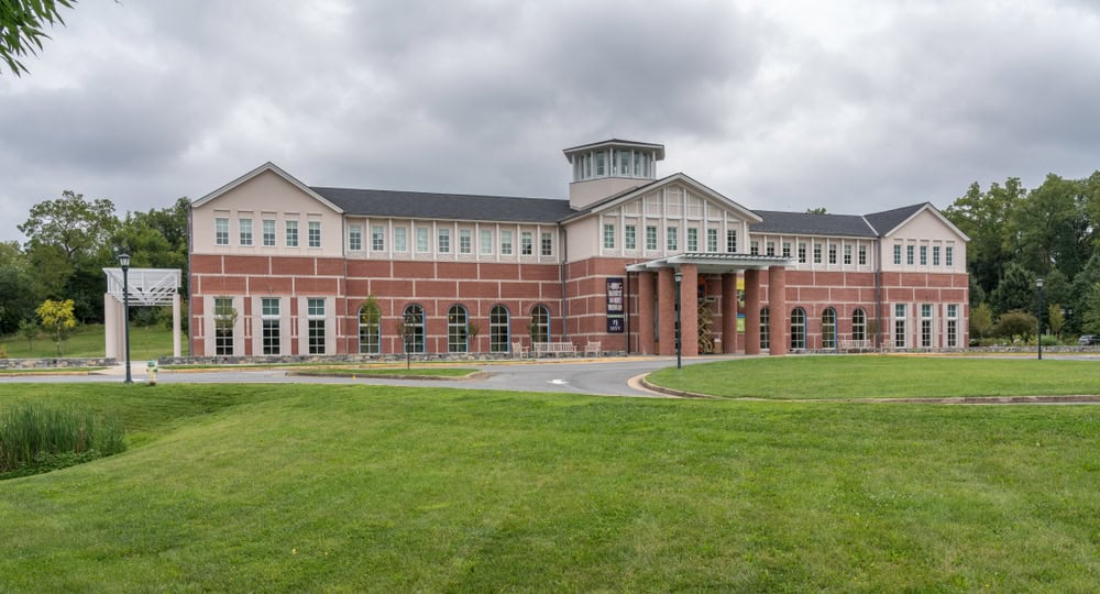 A large brick building with columns behind a landscaped lawn.