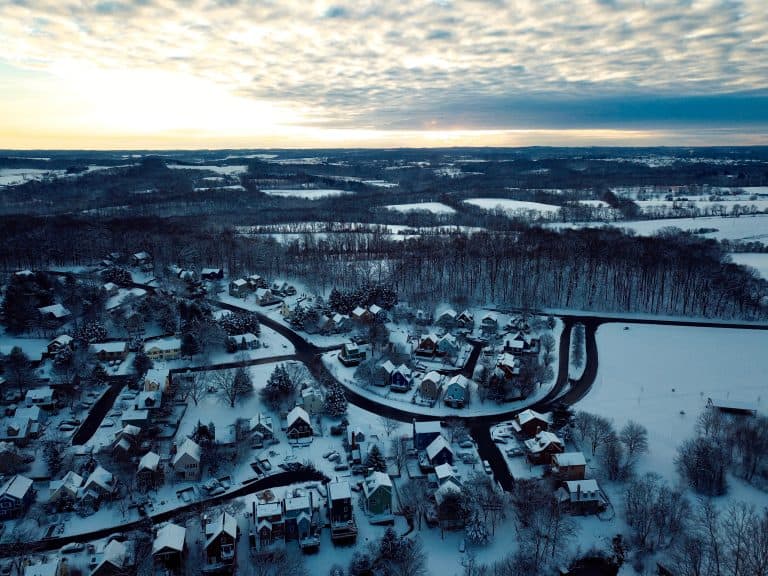 An aerial view of snow covered houses and rooftops in a New Market, Maryland neighborhood under a winter sky