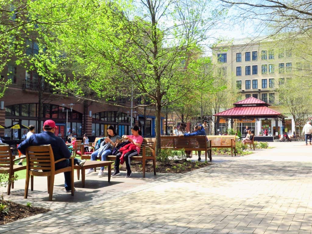 People relax on benches in the plaza at Rockville Town Square in Rockville, Maryland