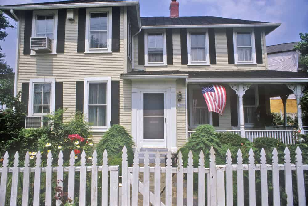 A two-story Victorian house with a white picket fence and an American flag in Glen Echo, Maryland
