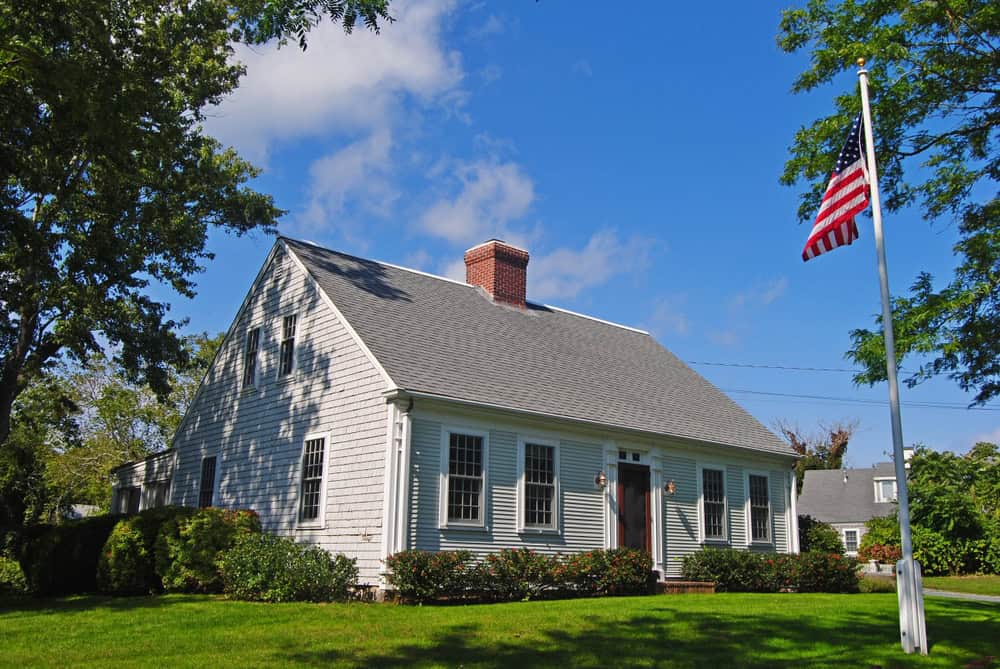 A white Cape Cod style home with a brick chimney and an American flag in the yard, Gainesboro, Virginia