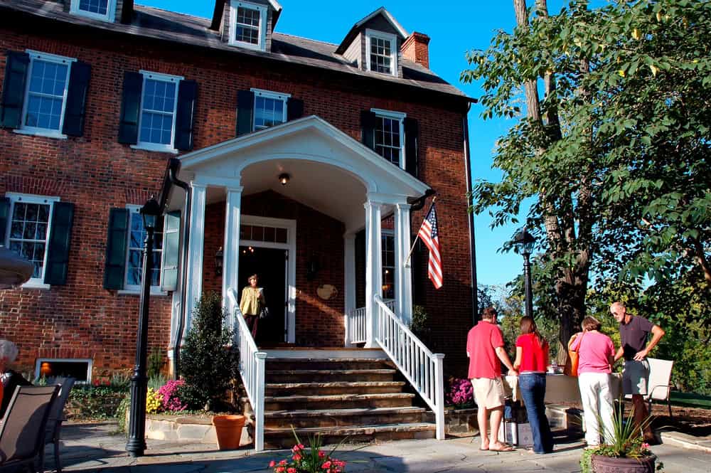 A brick colonial style building with a columned portico and visitors gathered outside in Haymarket, Virginia