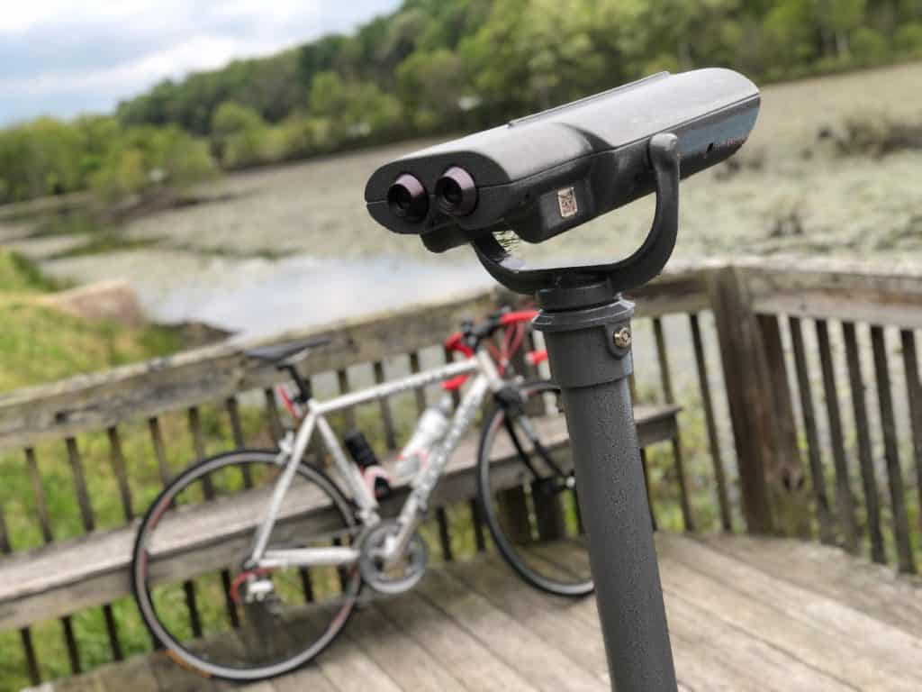 A coin operated viewing scope and a bicycle on a boardwalk overlooking wetlands near Indian Head, Maryland.