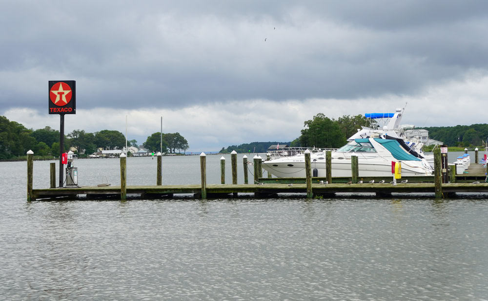 A docked cabin cruiser and a Texaco sign at a marina on the water near Cobb Island, Maryland.
