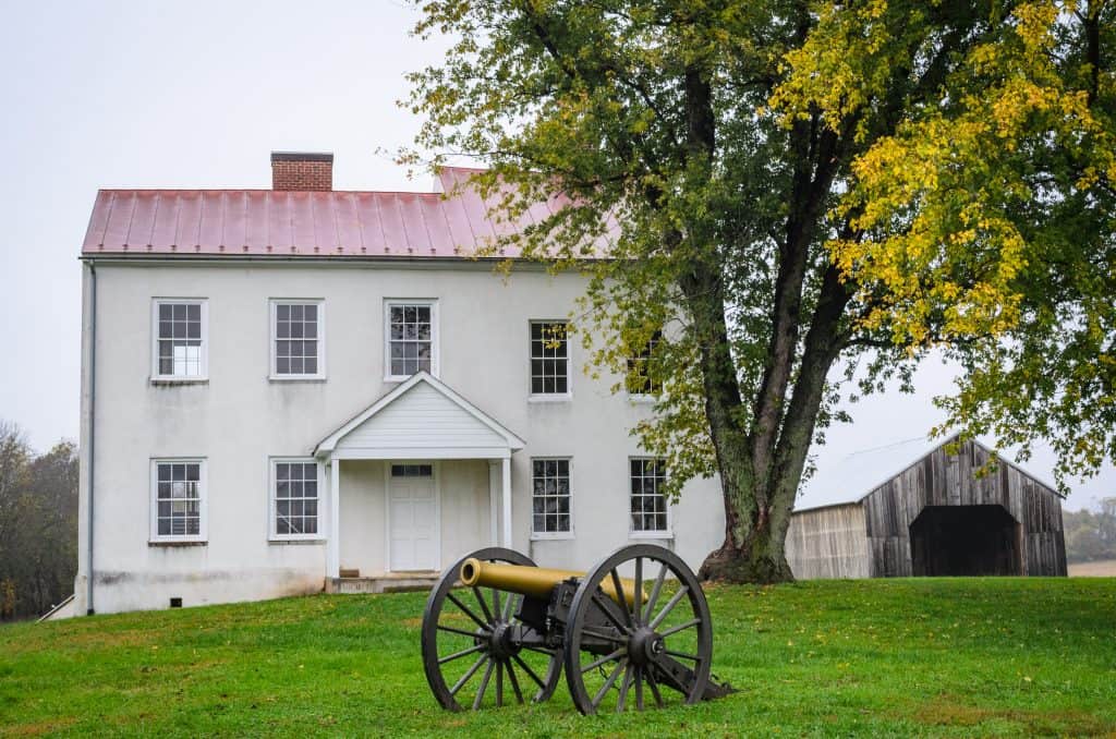 A white farmhouse and barn with an antique cannon at Monocacy National Battlefield in Frederick County, Maryland