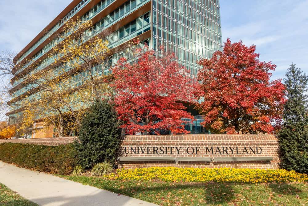 The University of Maryland campus building and entrance sign framed by red and gold autumn trees