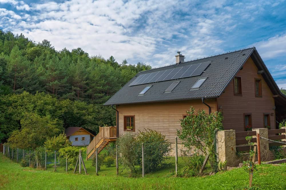A wood sided house with rooftop solar panels sits at the edge of a forest in Shawnee Land, Virginia
