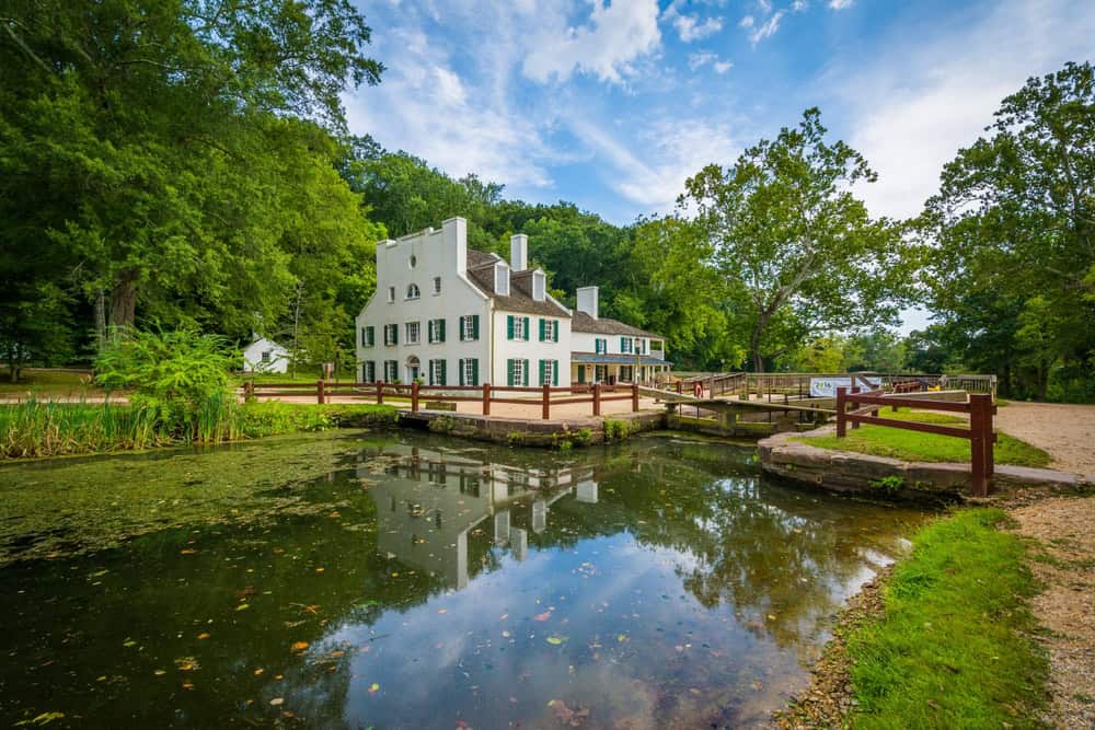 A white colonial-style lockhouse with green shutters beside the C&O Canal near Potomac, Maryland
