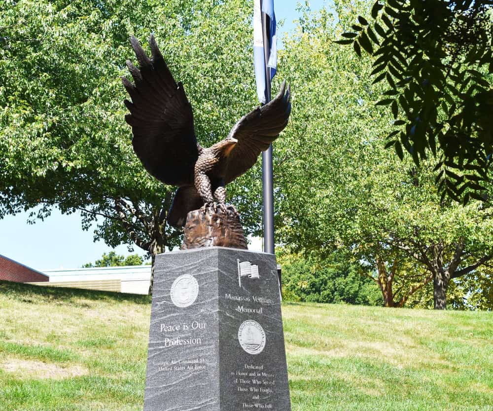 An eagle sculpture with outstretched wings above a stone veterans memorial.