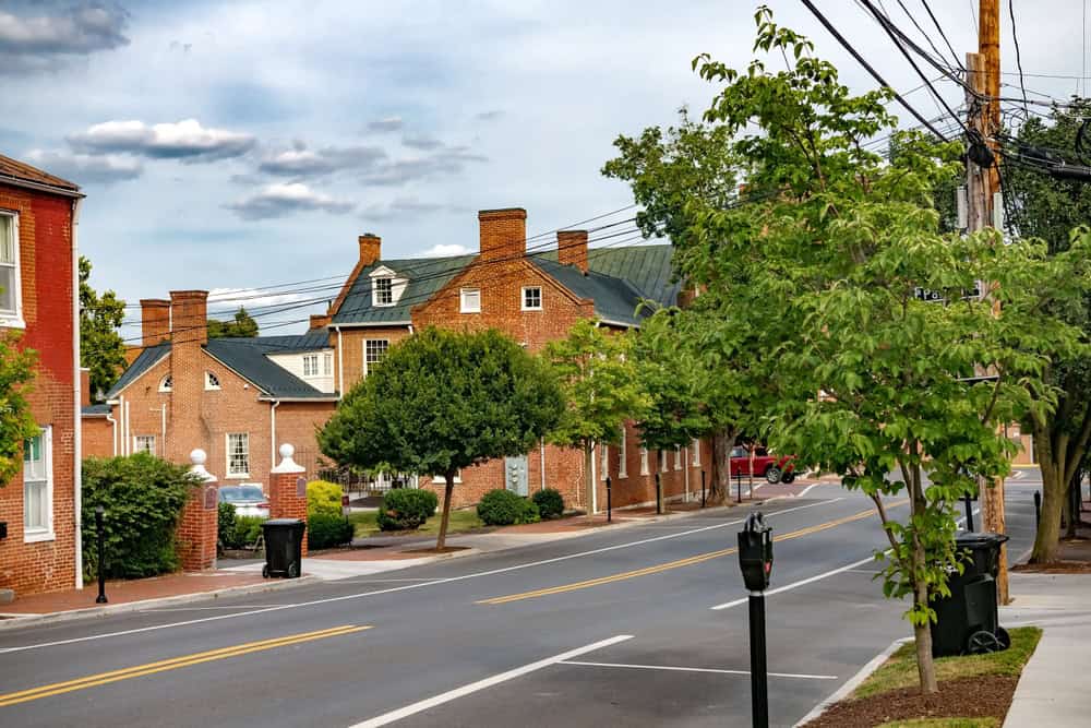 Large brick buildings with green roofs, dormers, and chimneys line a street in Winchester, Virginia