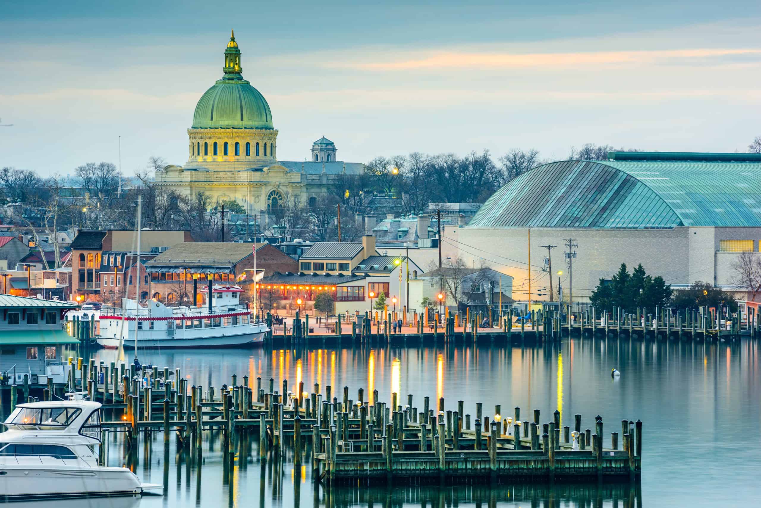 The Annapolis waterfront at dusk with the Naval Academy chapel dome rising above docked boats